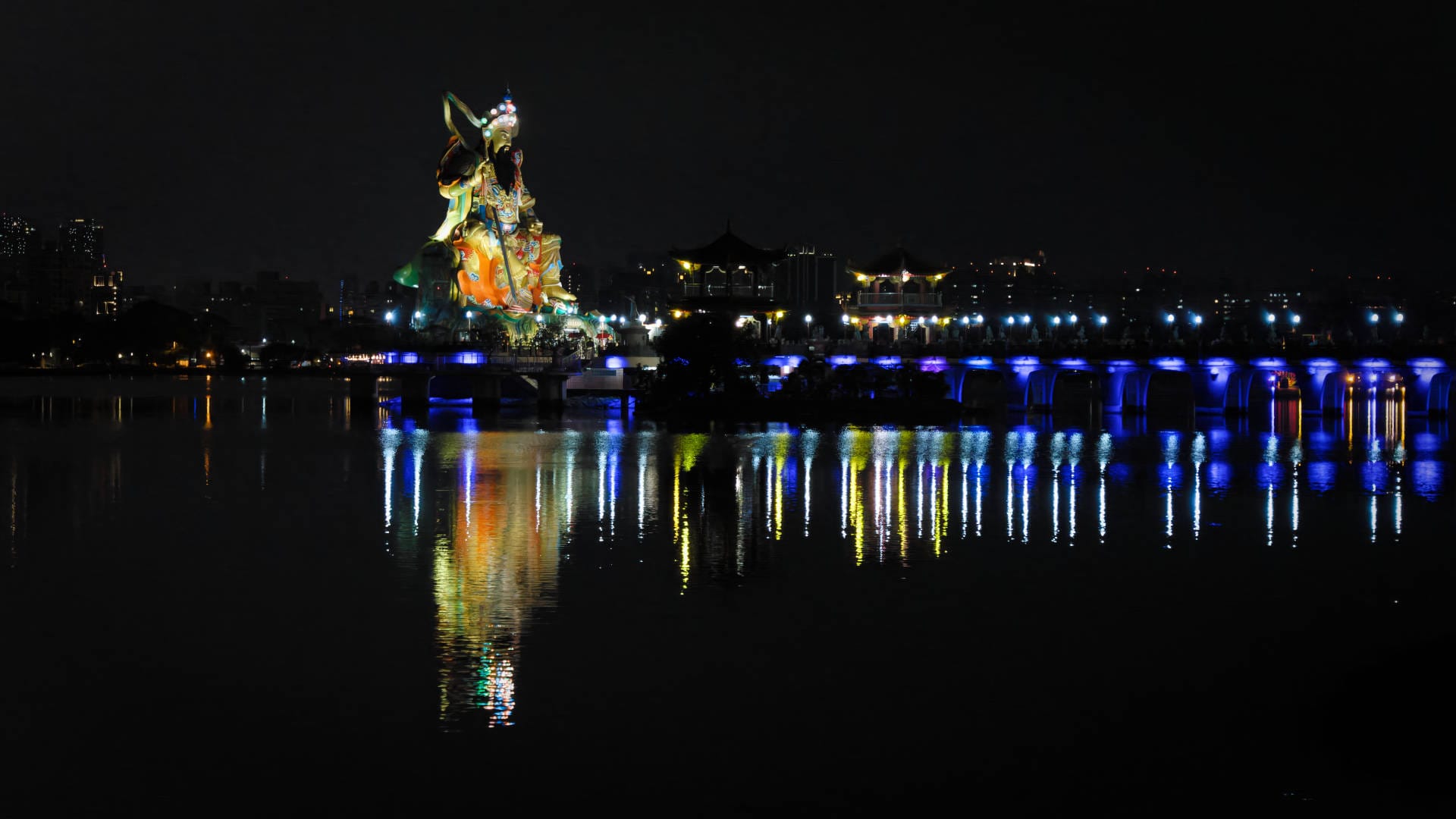 Nighttime photo of a large statue of Xuanwu, reflected in the still waters of Lotus Pond.