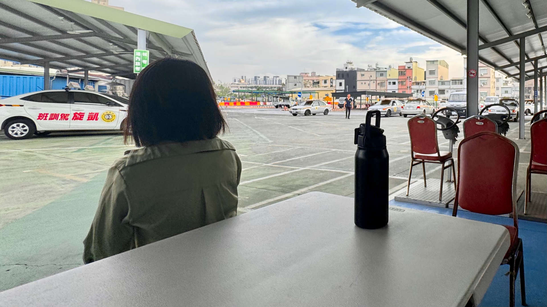 Student sitting with the back to the camera, at an outdoor driving school test track in Kaohsiung, Taiwan.