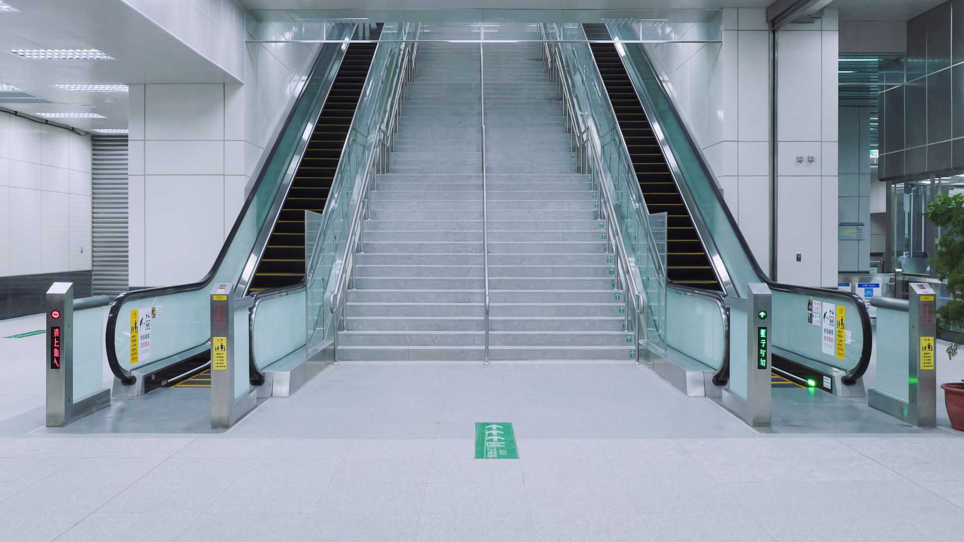 Symmetrical view of two escalators with a pristine wide staircase in between.