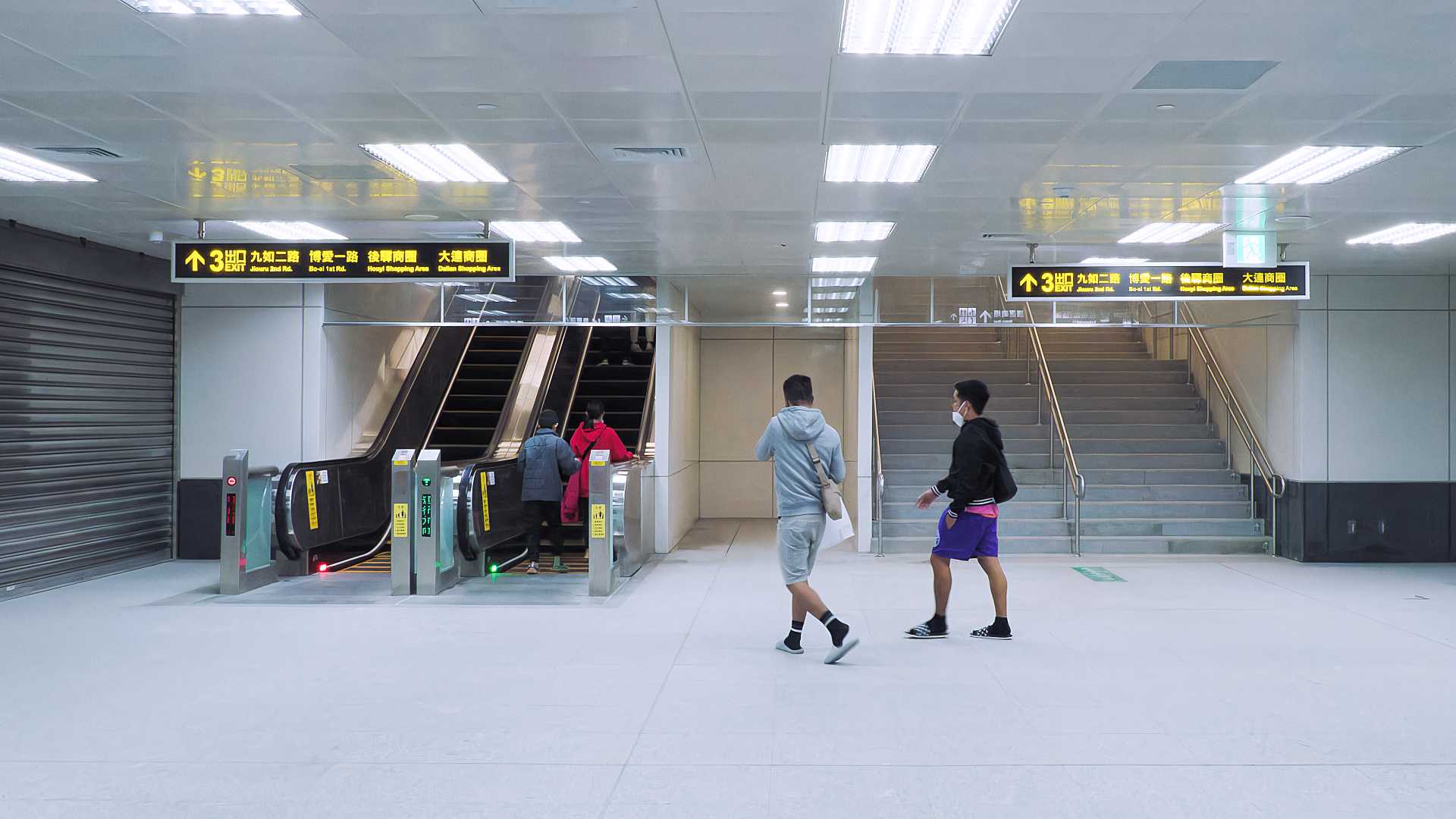 Metro passengers walking towards an escalator at Kaohsiung Station.