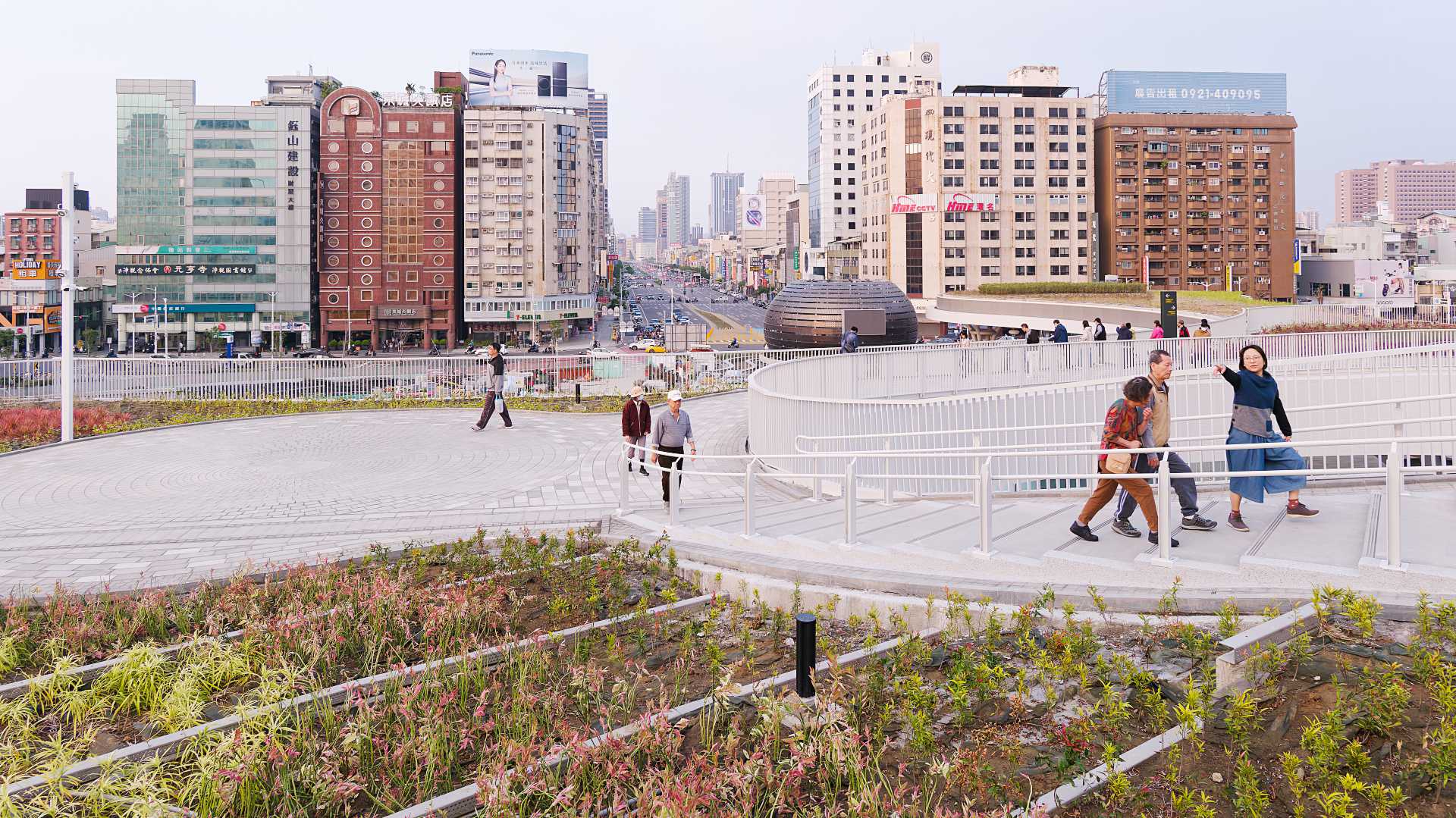 People exploring the expansive rooftop garden at Kaohsiung Station.