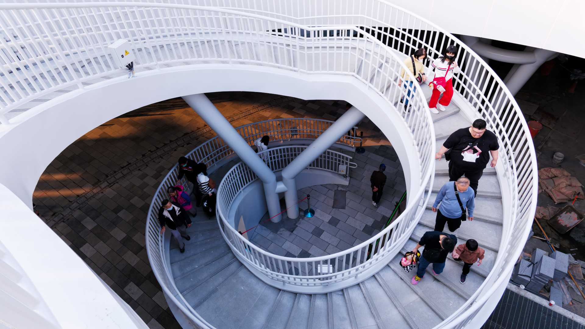 A group of people descending a spiral staircase.