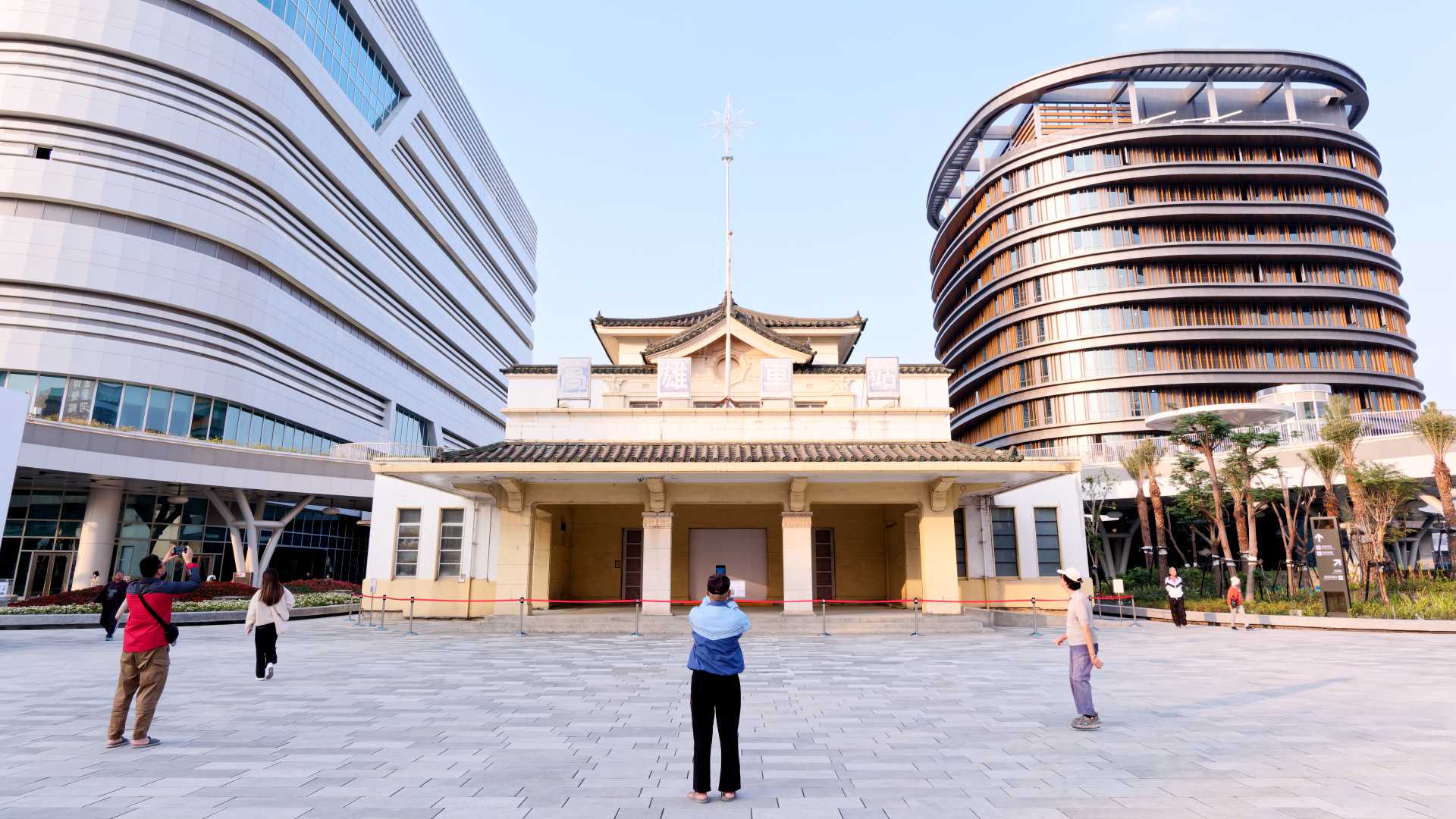 A man takes a photo of the old Kaohsiung Station building, now flanked by two new towers.