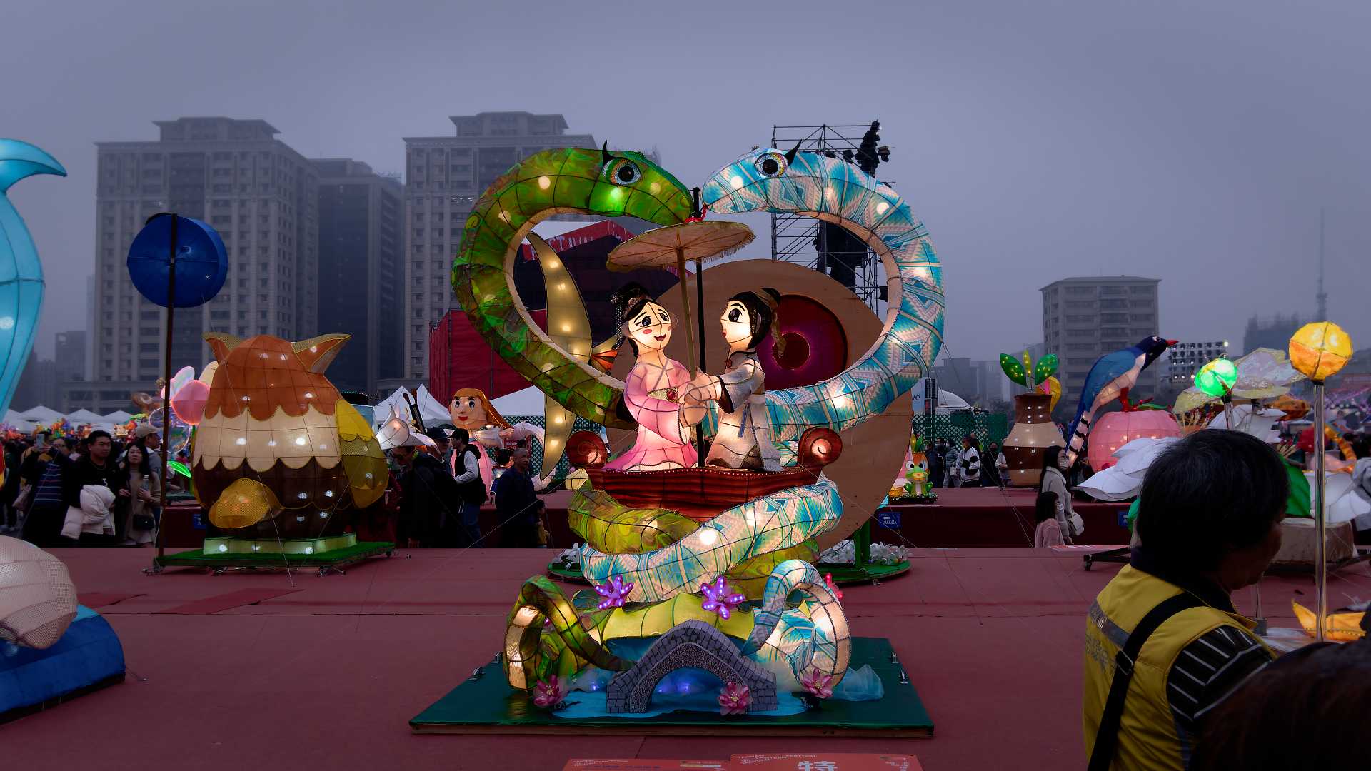 Lantern in the shape of two folk characters in love, surrounded by snakes forming a heart shape.