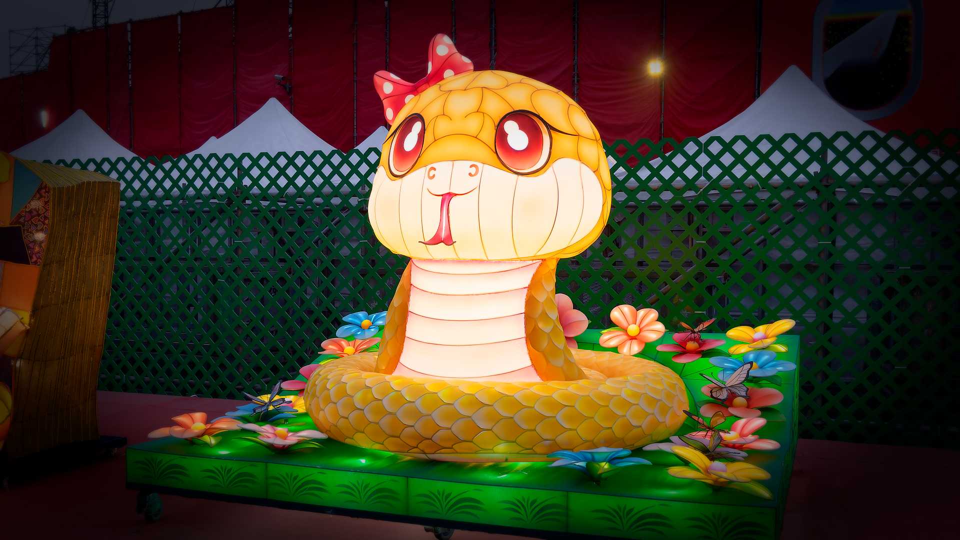 Lantern in the shape of a cartoon snake in a flower garden.