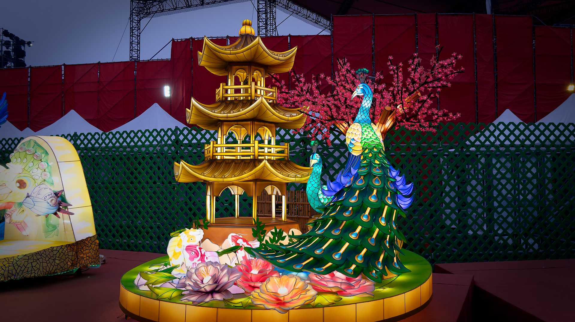 Lantern in the shape of a peacock next to a golden pagoda.