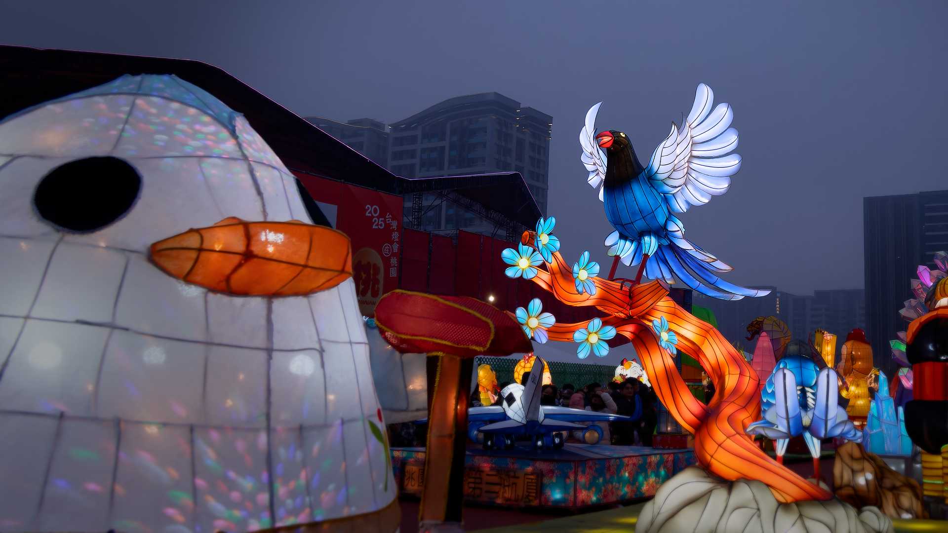 Lantern in the shape of a bird with outstretched wings, perched atop a branch.