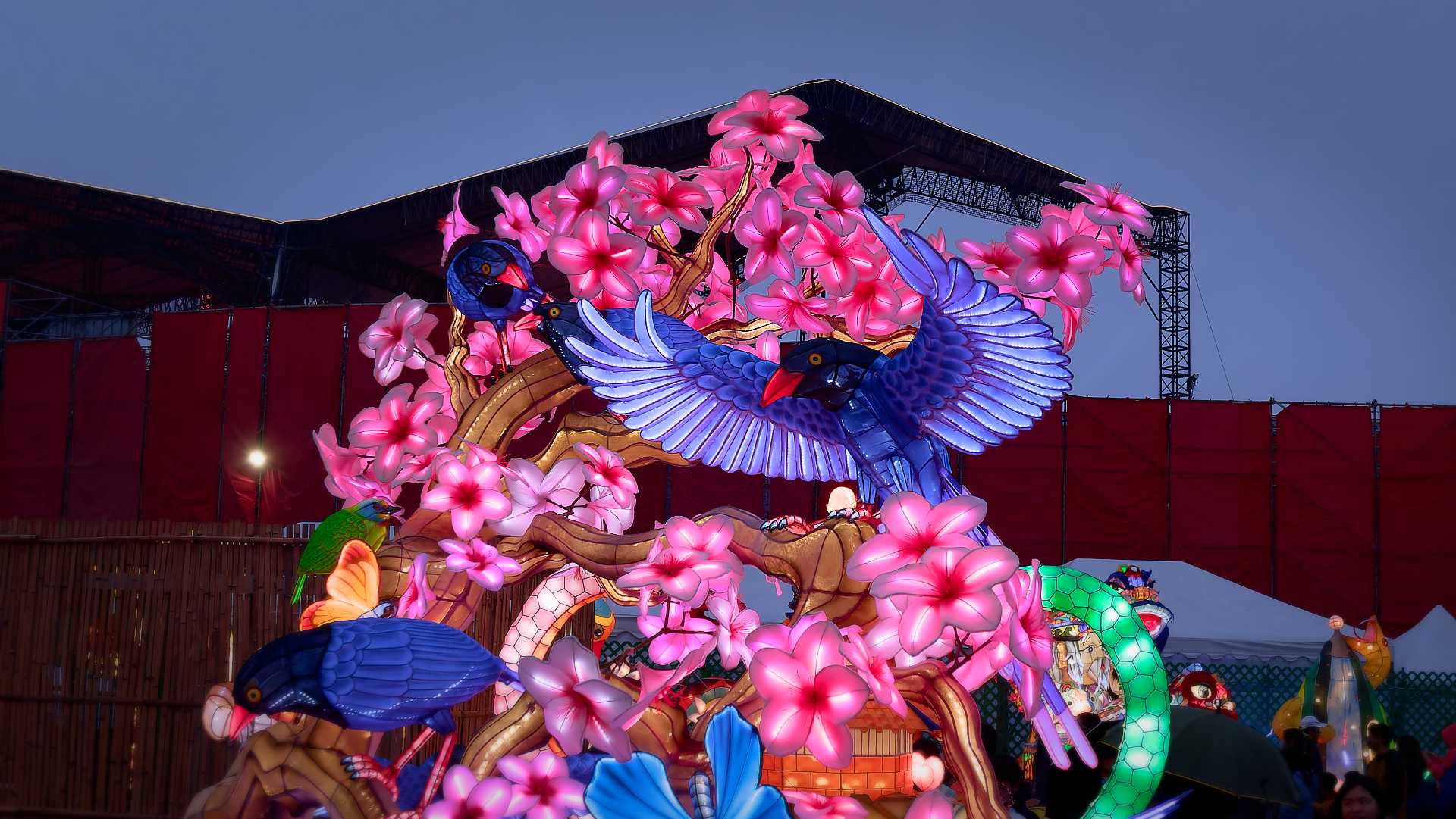 Lantern in the shape of a bird with outstretched wings, in a blossoming tree.