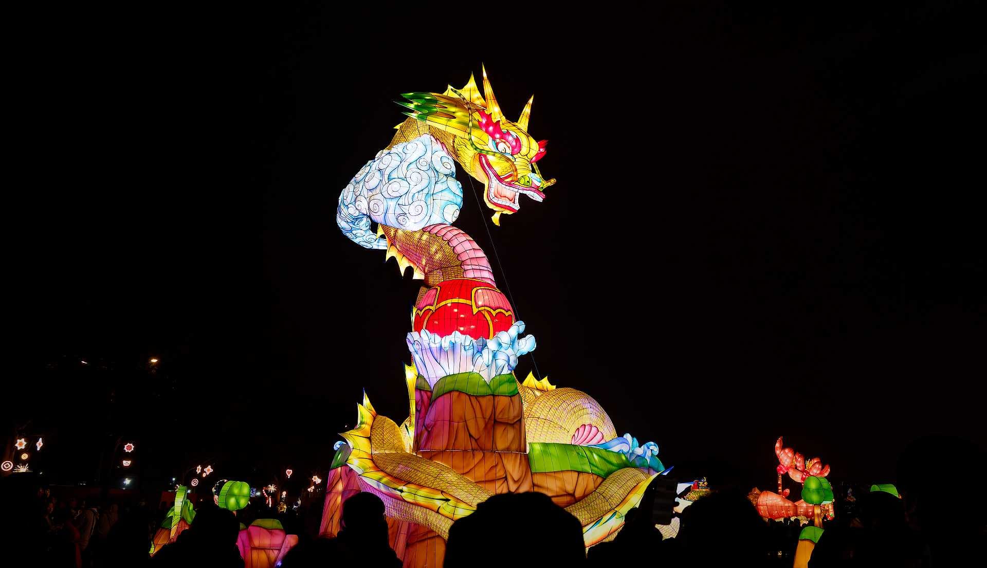 Lantern in the shape of a large dragon looking down on the crowd.