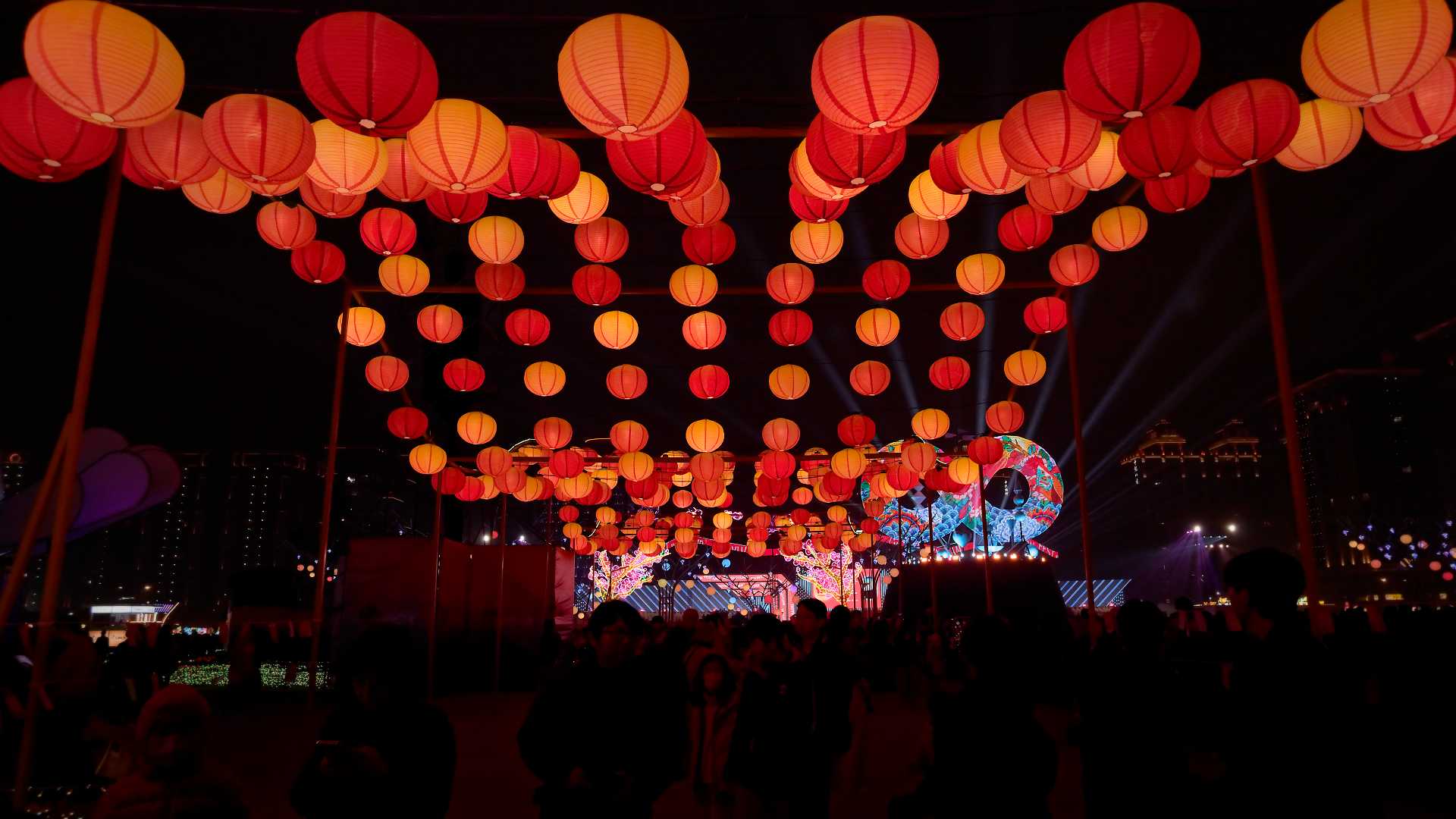 Hundreds of red and orange lanterns hanging from a pagoda, in a wave-like pattern.