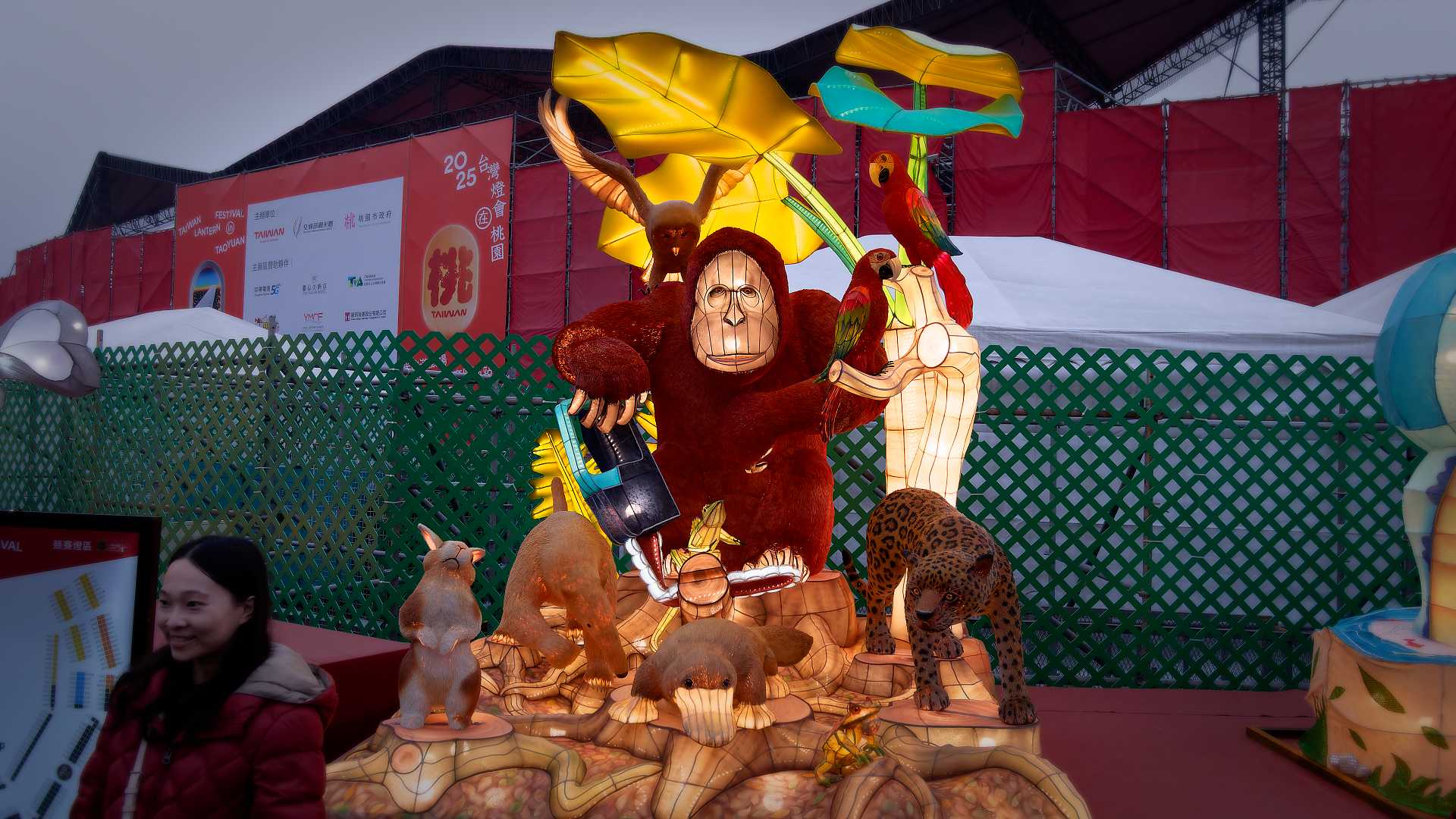 Lantern in the shape of a gorilla using a damaged chainsaw to cut wood, while surrounded by other animals.