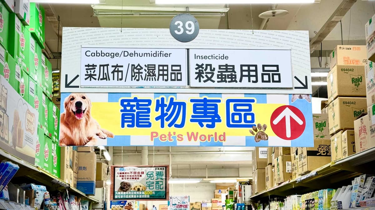 Sign hanging above a supermarket aisle, which reads ‘Cabbage/Dehumidifier’.