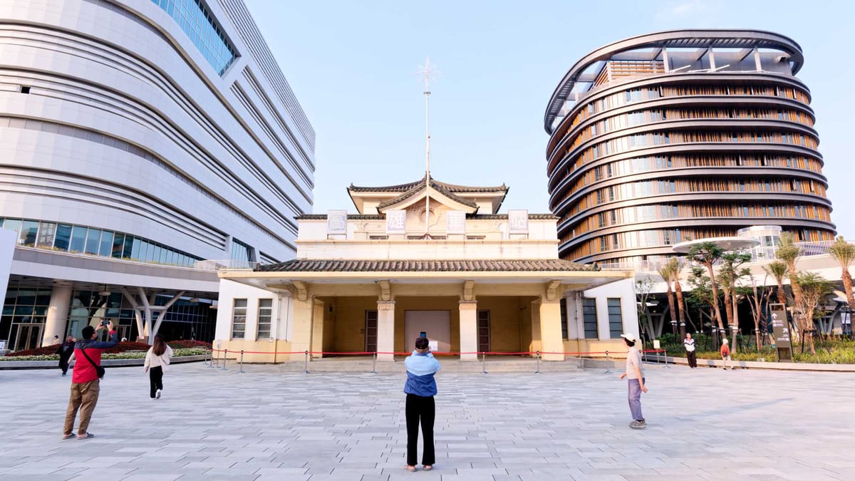 A man takes a photo of the old Kaohsiung Station building, now flanked by two new towers.