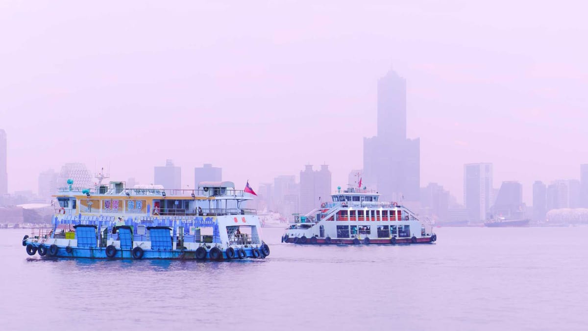 Two scooter ferries passing each other on Kaohsiung Harbor. The city skyline is visible in the distance, through the haze.